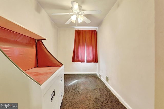 interior space featuring a ceiling fan, dark colored carpet, visible vents, and baseboards