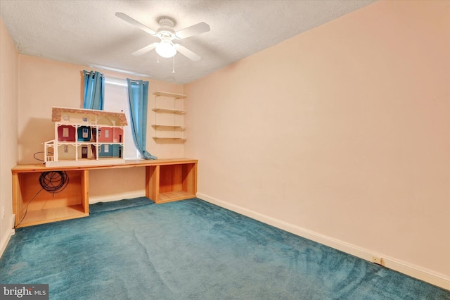 unfurnished office featuring a textured ceiling, ceiling fan, carpet flooring, baseboards, and built in desk