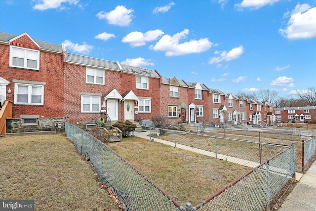 view of property with fence private yard, brick siding, a residential view, and a front yard