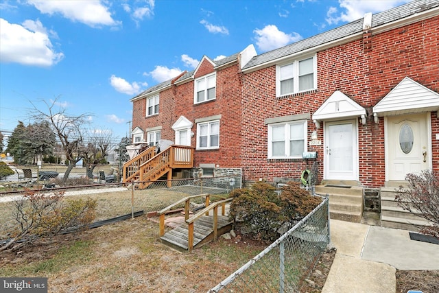 view of front facade featuring entry steps, brick siding, and fence private yard