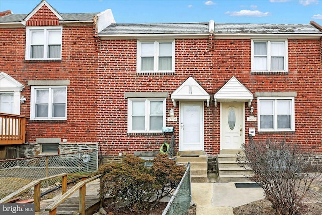 townhome / multi-family property featuring entry steps, brick siding, and fence