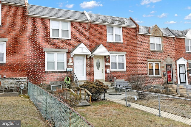 view of property featuring entry steps, a fenced backyard, a high end roof, a front lawn, and brick siding