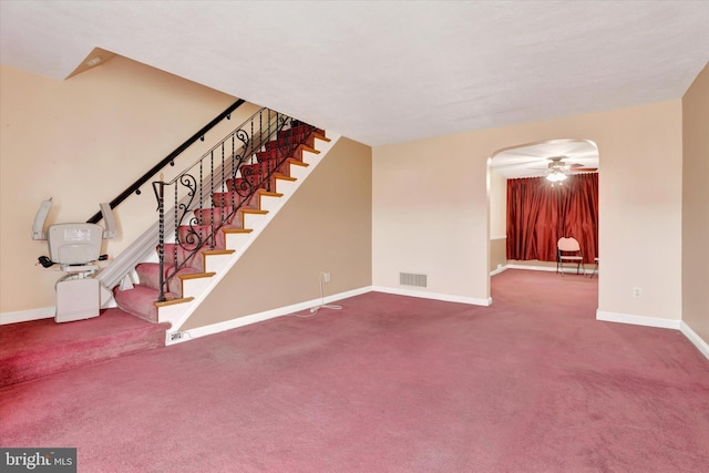 unfurnished living room featuring arched walkways, visible vents, baseboards, and stairs