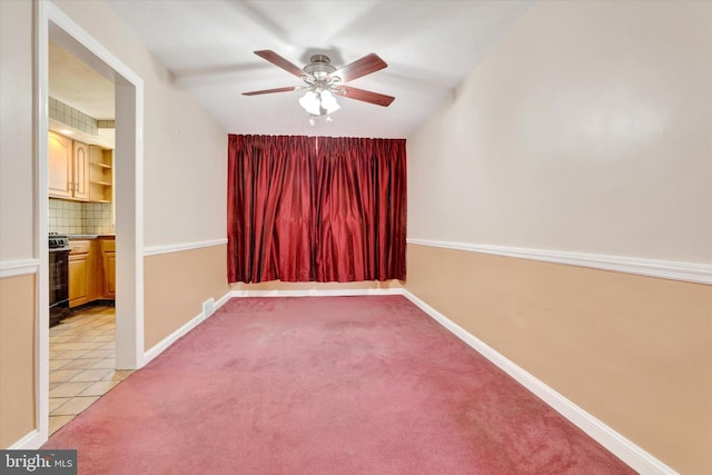 empty room featuring light colored carpet, ceiling fan, baseboards, and light tile patterned floors