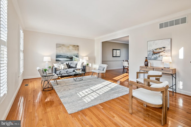 living room with visible vents, crown molding, baseboards, and hardwood / wood-style flooring