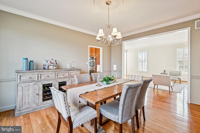 dining area featuring light wood finished floors, visible vents, ornamental molding, and a notable chandelier