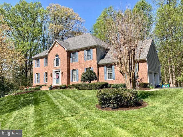 colonial home featuring a garage, brick siding, and a front lawn