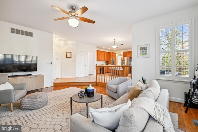 living room featuring baseboards, plenty of natural light, visible vents, and light wood-style floors