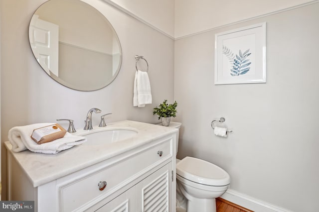 half bathroom with toilet, baseboards, and vanity