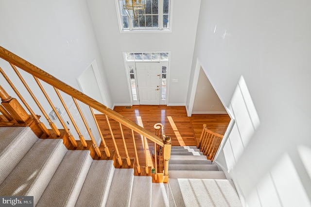 stairs with a towering ceiling, baseboards, and wood finished floors