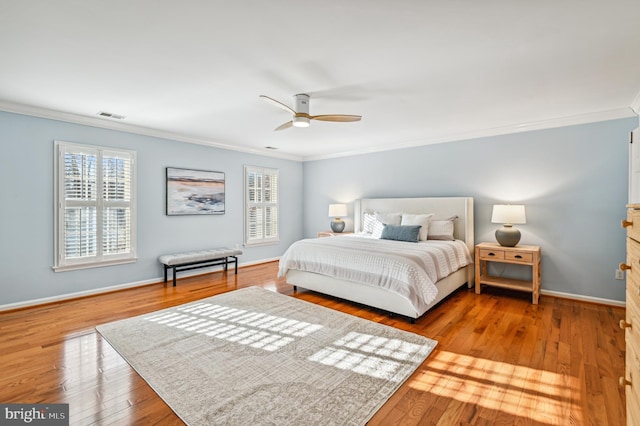 bedroom with baseboards, visible vents, a ceiling fan, wood-type flooring, and crown molding