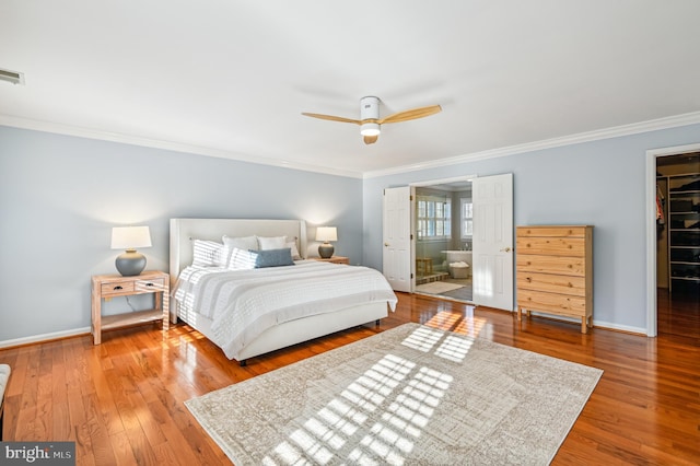 bedroom with ornamental molding, hardwood / wood-style floors, a walk in closet, and baseboards