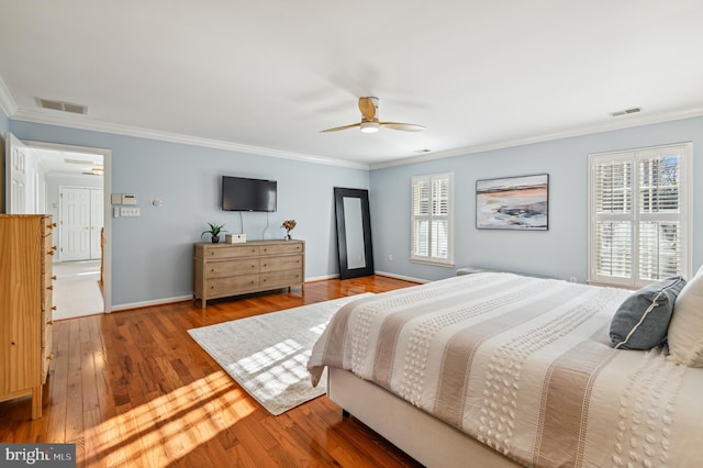 bedroom featuring multiple windows, hardwood / wood-style flooring, visible vents, and crown molding