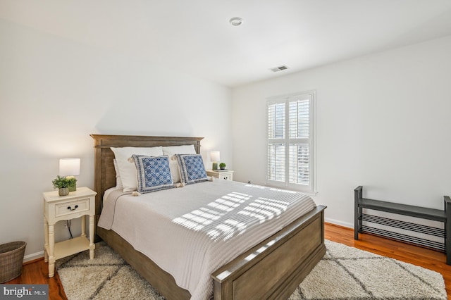 bedroom featuring wood finished floors, visible vents, and baseboards