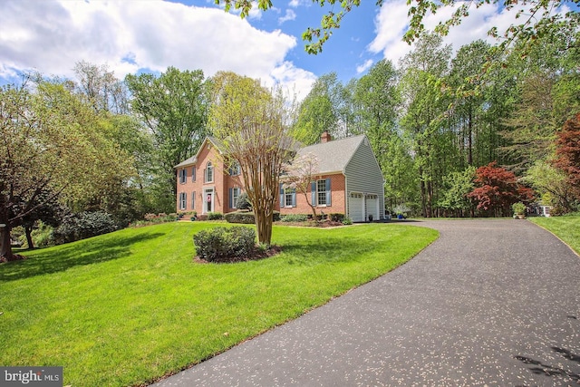 colonial inspired home with brick siding, aphalt driveway, and a front yard