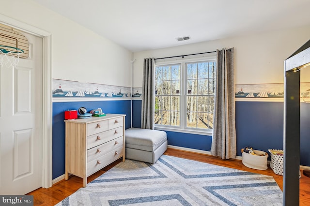 bedroom with baseboards, visible vents, and wood finished floors