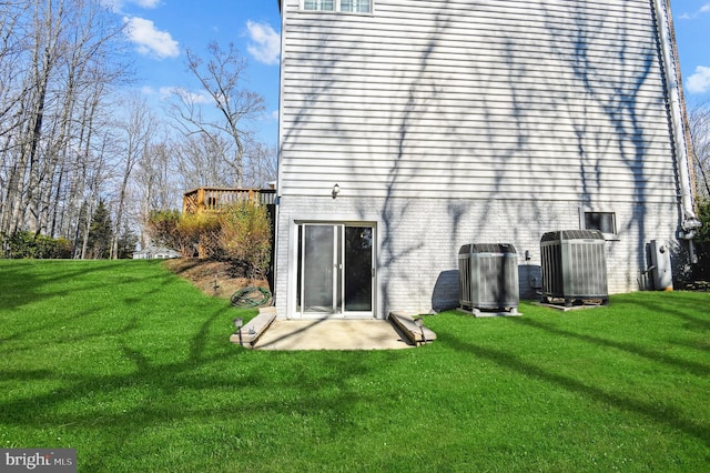 rear view of house featuring a lawn, cooling unit, and brick siding