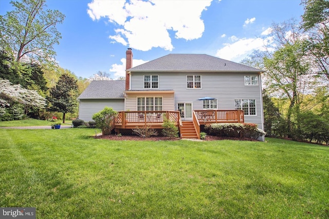 rear view of property featuring a yard, a chimney, and a wooden deck