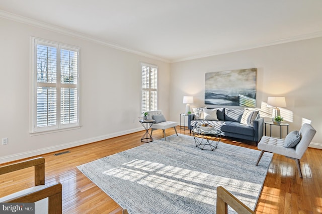 living room with baseboards, hardwood / wood-style floors, visible vents, and crown molding