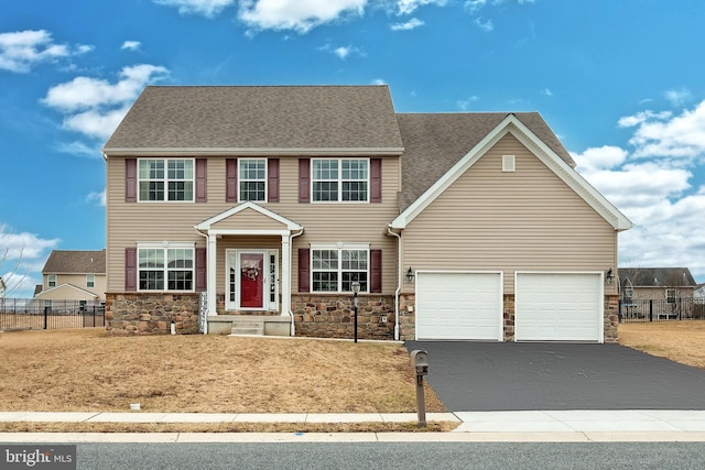 view of front of property with aphalt driveway, stone siding, and fence