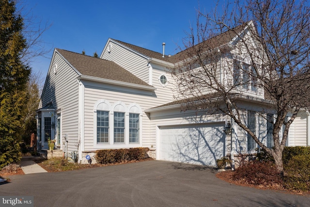 view of front of home featuring a garage, roof with shingles, and aphalt driveway