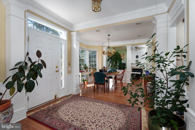 foyer entrance featuring wainscoting, crown molding, ornate columns, and wood finished floors