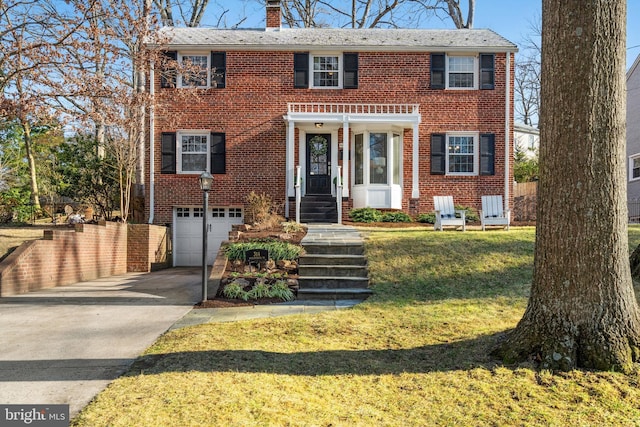 view of front of property with brick siding, a chimney, concrete driveway, a front yard, and a garage