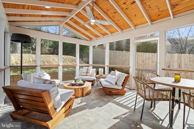 sunroom / solarium with a ceiling fan, a wealth of natural light, wood ceiling, and lofted ceiling with beams