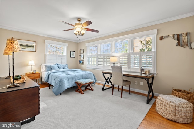 bedroom featuring a ceiling fan, crown molding, baseboards, and wood finished floors