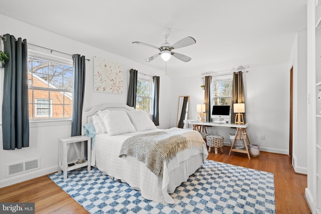 bedroom featuring a ceiling fan, wood finished floors, visible vents, and baseboards