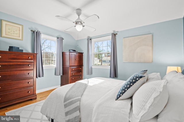 bedroom featuring multiple windows, wood finished floors, a ceiling fan, and baseboards