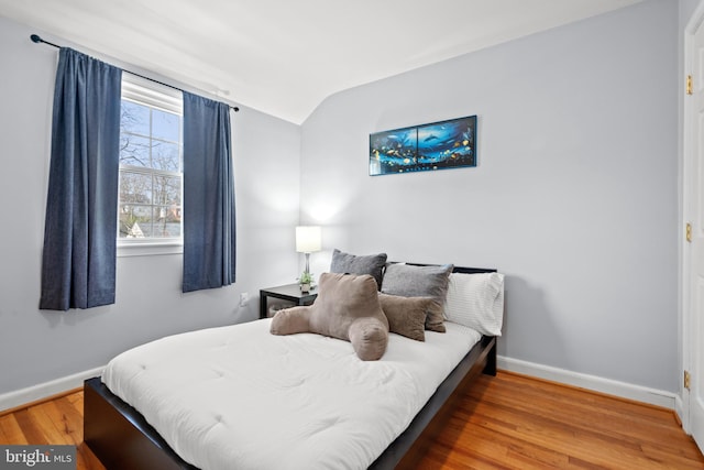 bedroom featuring lofted ceiling, baseboards, and wood finished floors