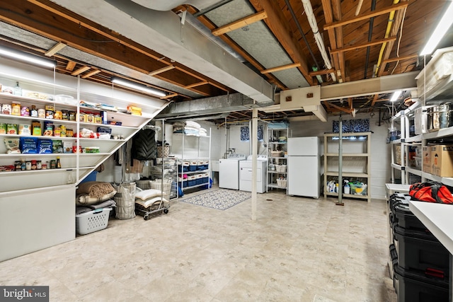 unfinished basement featuring freestanding refrigerator, tile patterned floors, and separate washer and dryer