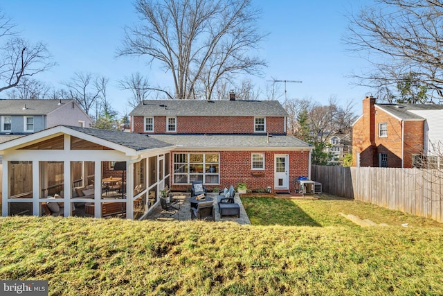 back of house with brick siding, a chimney, a lawn, a sunroom, and fence