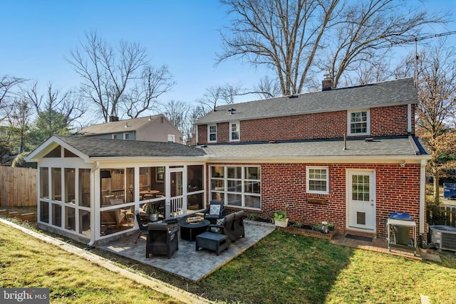 rear view of house with a yard, a sunroom, brick siding, and a patio