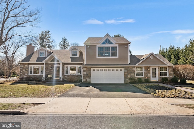 view of front of house with aphalt driveway, an attached garage, stone siding, and a chimney