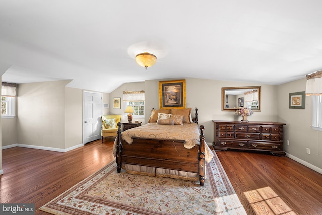 bedroom featuring multiple windows, lofted ceiling, baseboards, and wood finished floors