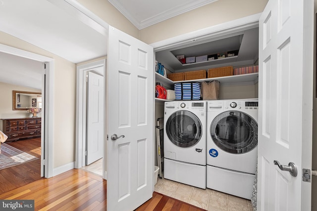 laundry room featuring laundry area, ornamental molding, light wood-type flooring, and separate washer and dryer