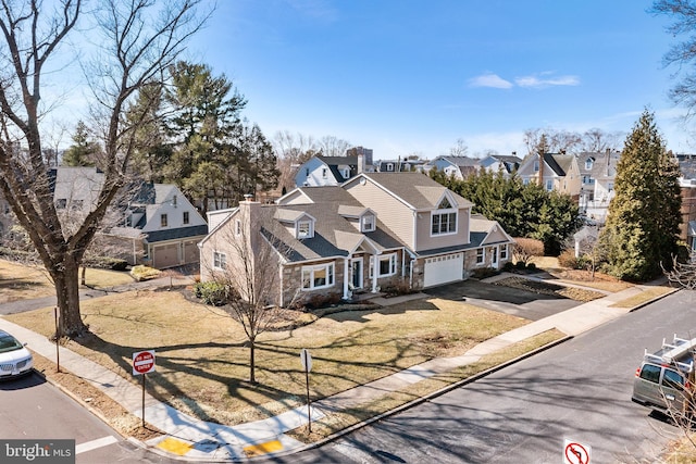 view of front of house with a front yard, a garage, stone siding, aphalt driveway, and a residential view