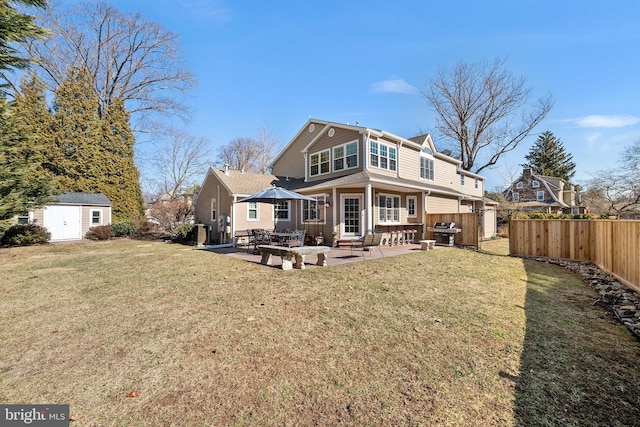 rear view of house with a patio, a fenced backyard, a shed, a yard, and an outdoor structure