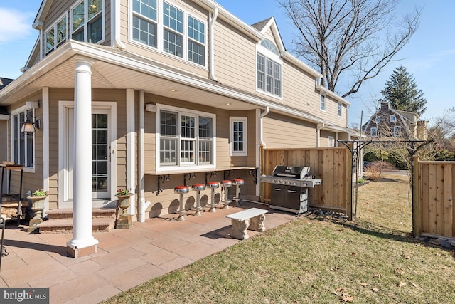 rear view of house featuring a patio area, a yard, and fence