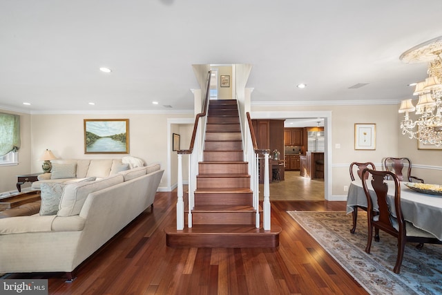 stairway featuring hardwood / wood-style flooring, a notable chandelier, baseboards, and ornamental molding