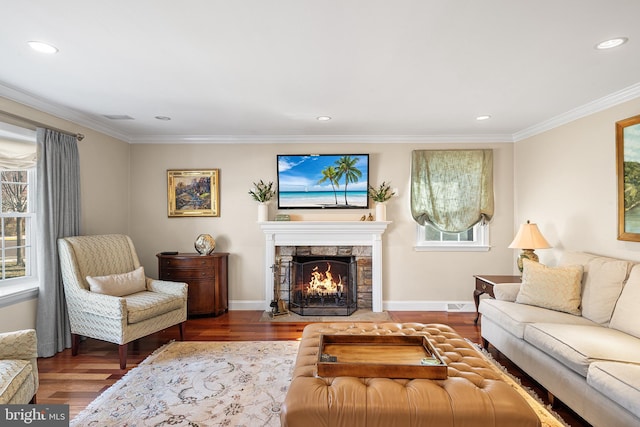 living area with a fireplace, wood finished floors, a wealth of natural light, and ornamental molding