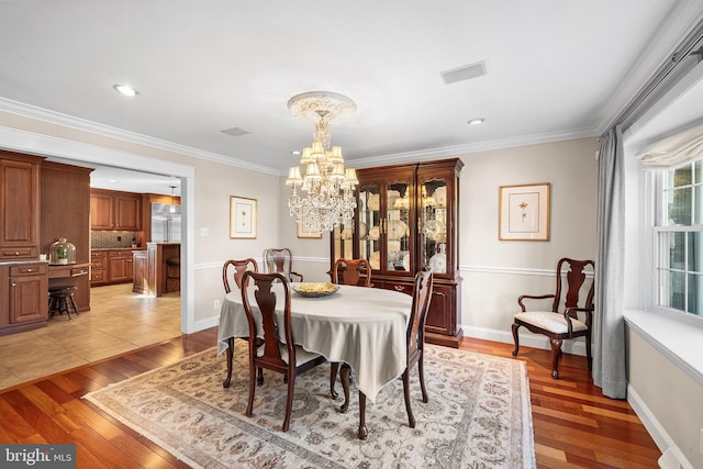 dining area with visible vents, baseboards, an inviting chandelier, light wood-style flooring, and ornamental molding