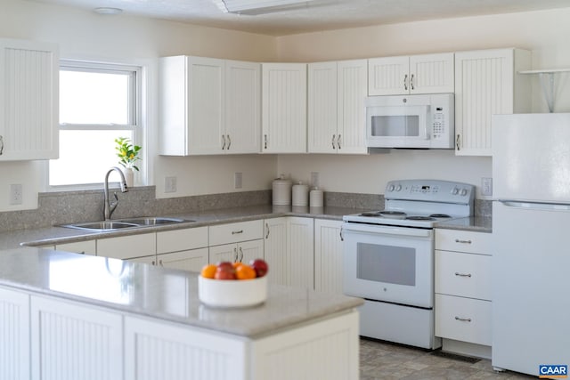 kitchen featuring white appliances, white cabinets, a sink, and light countertops