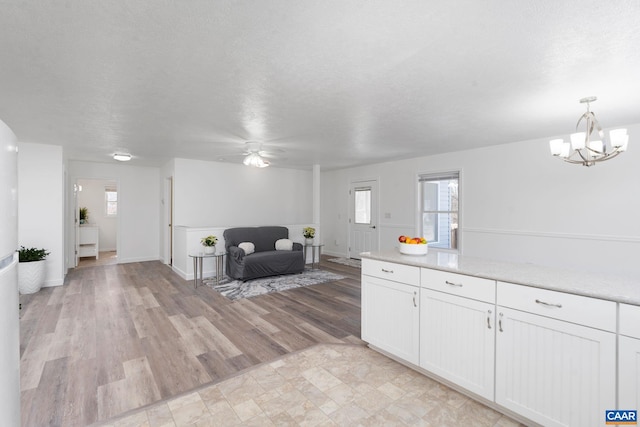 interior space with light wood-style flooring, white cabinetry, open floor plan, and a textured ceiling