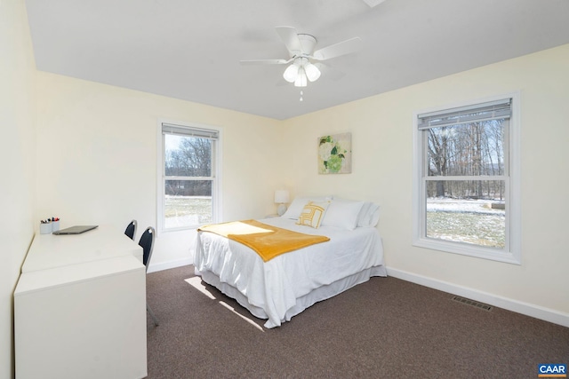 bedroom with a ceiling fan, dark carpet, visible vents, and baseboards