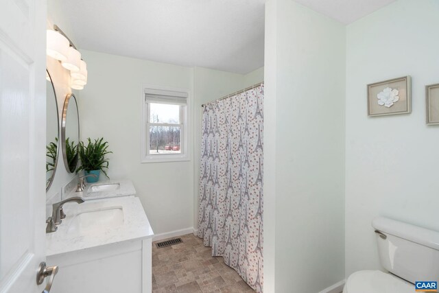 full bathroom featuring toilet, double vanity, a sink, and visible vents