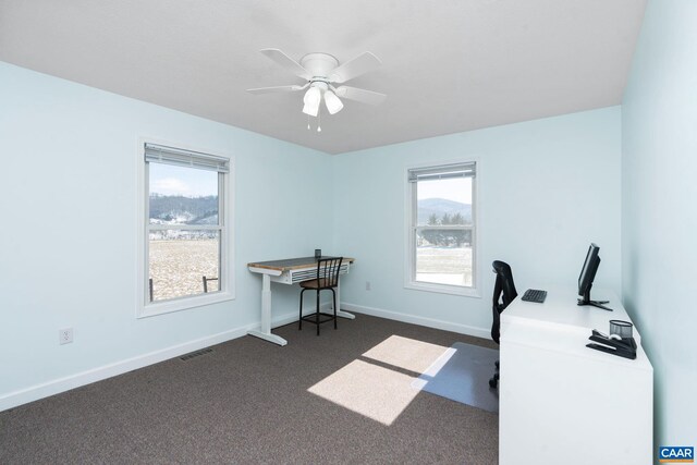 office space featuring a ceiling fan, dark colored carpet, visible vents, and baseboards