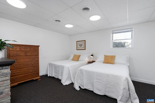 bedroom featuring visible vents, dark carpet, and a drop ceiling